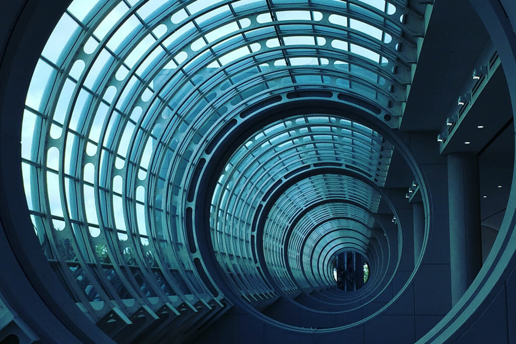 Futuristic glass and steel tunnel with circular arches and blue lighting, designed to embody precision and quality management in every detail.