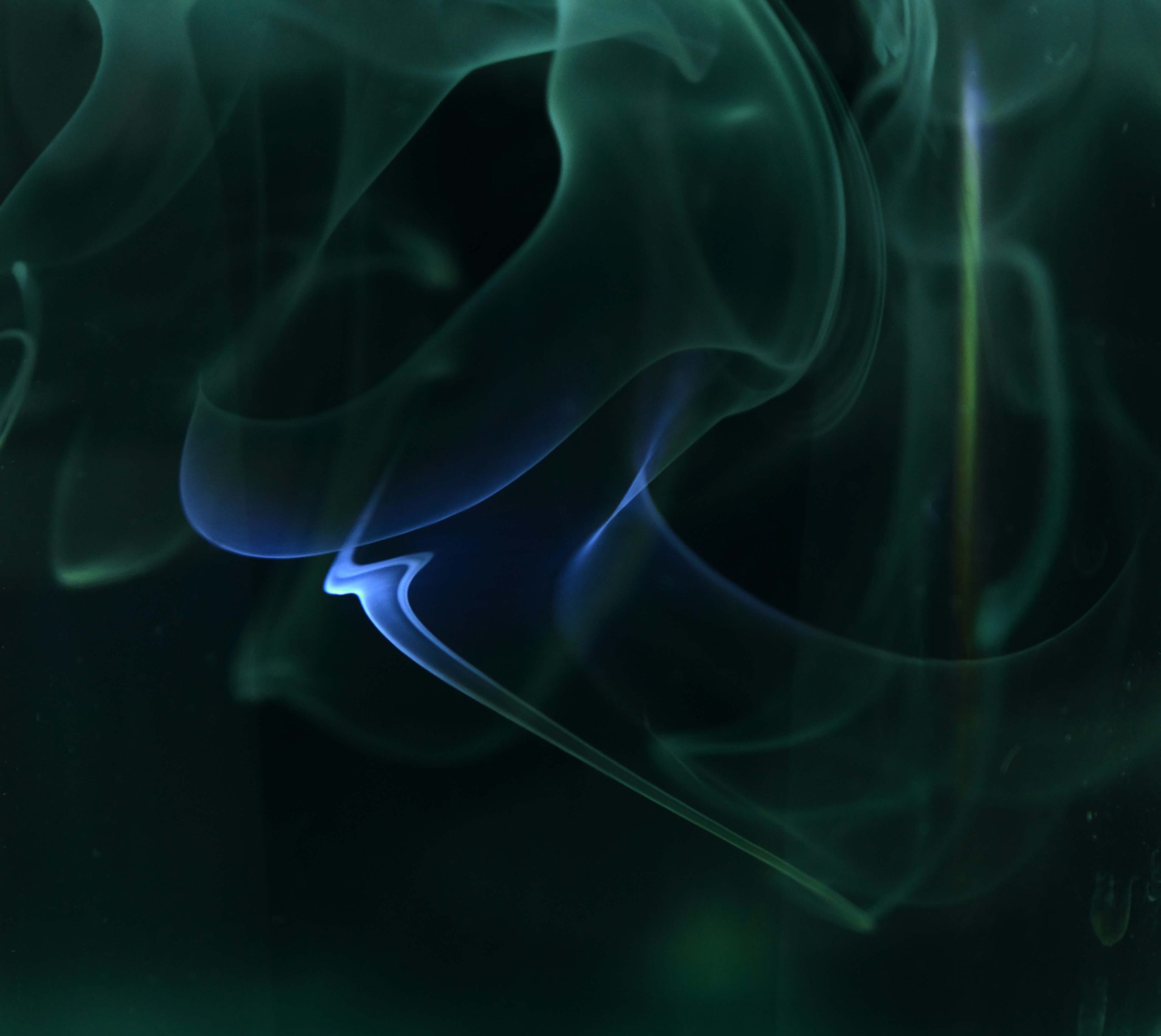 Wisps of blue and green smoke swirl abstractly against a dark background, evoking the dynamic flow of user experience in multilingual UX design.