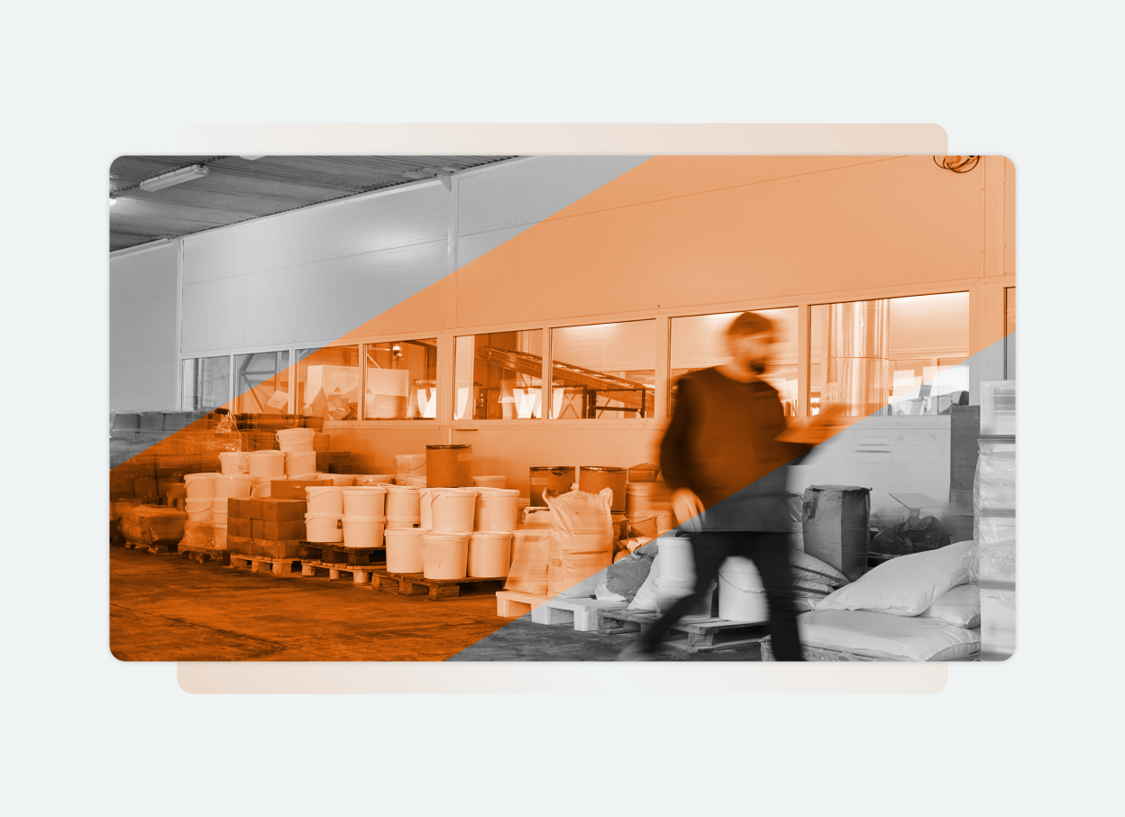 A blurred person walks through a warehouse filled with stacked bags and barrels, large windows in the background. An orange diagonal overlay effect adds emphasis, reflecting the vibrant energy of a busy solutions platform in action.