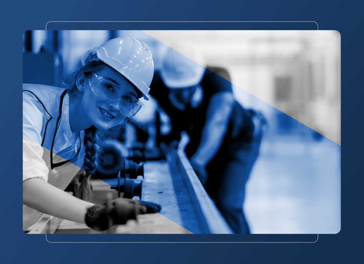 A woman wearing a hard hat, safety glasses, and gloves smiles while working with machinery in a food industry factory. In the background, another worker is adjusting equipment. The image has a blue and grayscale overlay.