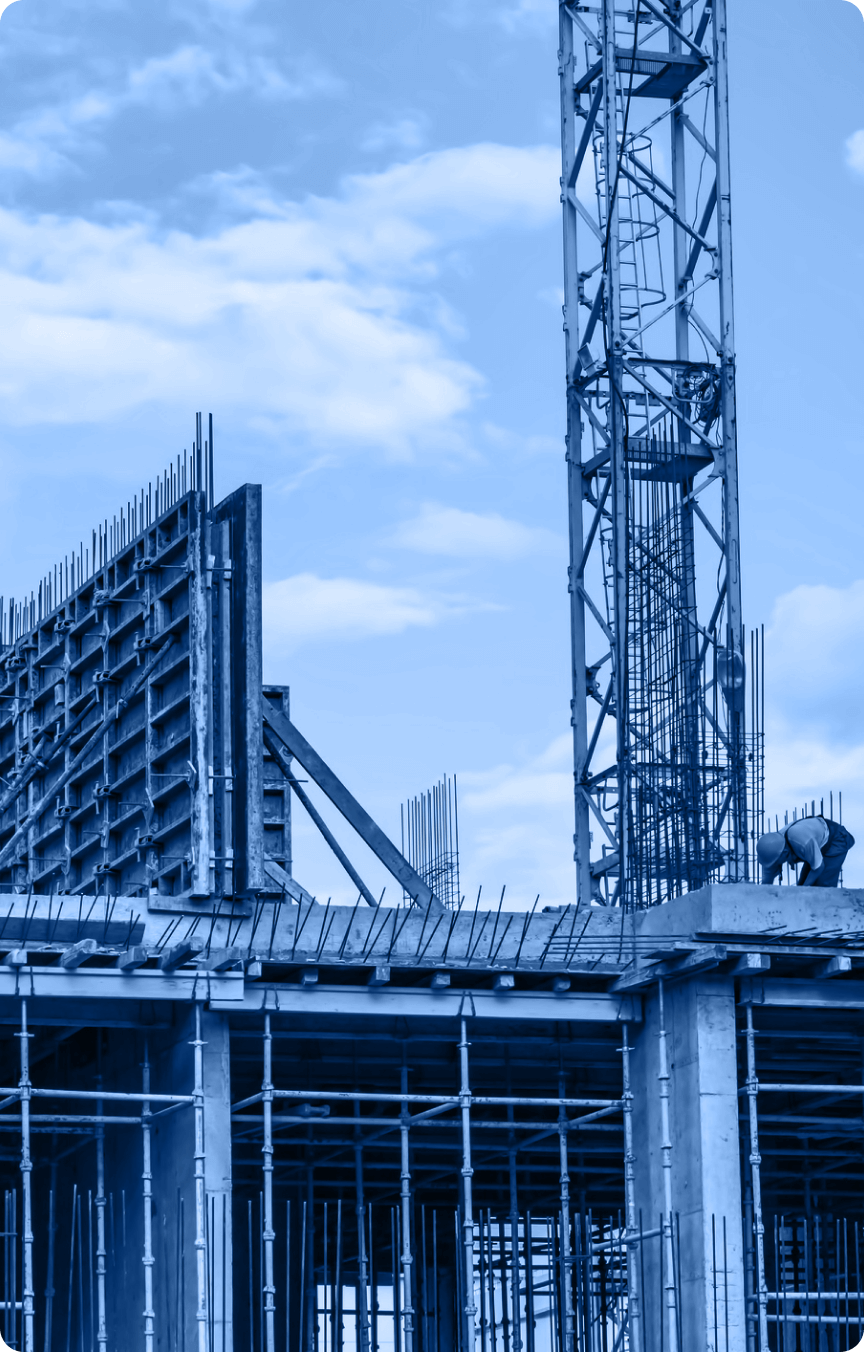 A construction site with steel framework, scaffolding, and a tower crane showcases the dynamic industry under a blue sky with scattered clouds.