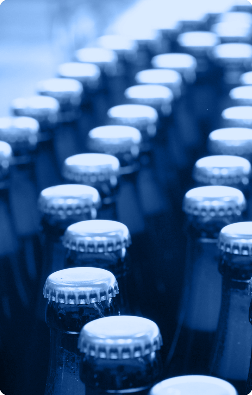 Rows of glass bottles with metal caps are arranged closely together, viewed from above at an angle. The image has a blue tint, giving it a cool, monochromatic look—ideal for use in an Industry Section or Industry Tab on a website.