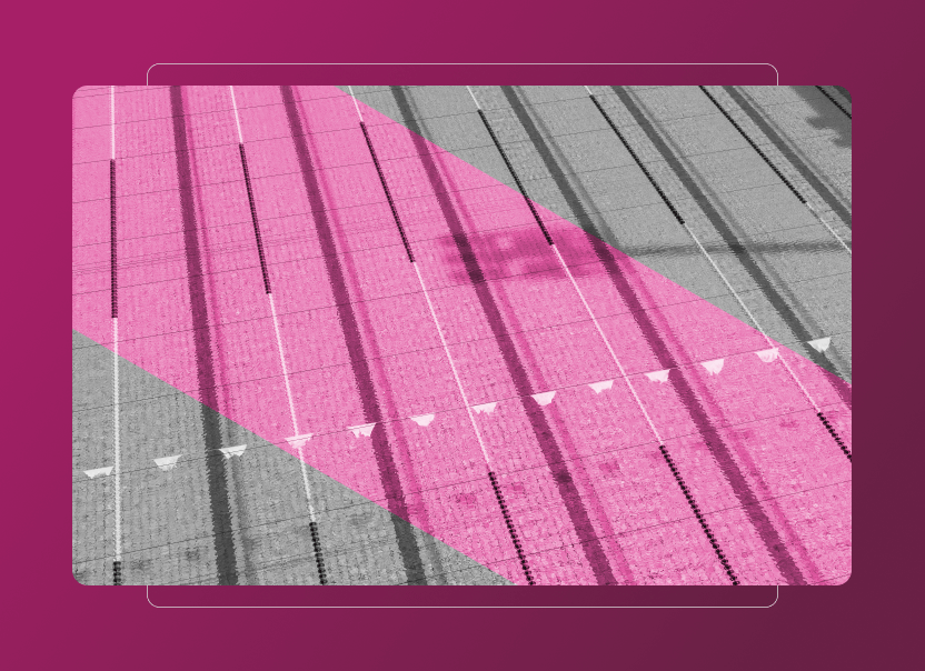 Overhead view of an empty indoor swimming pool with lane dividers and flags, mostly in grayscale, except for a large pink diagonal overlay across the pool. A subtle Sustainability Cloud effect enhances the pink gradient background surrounding the image.