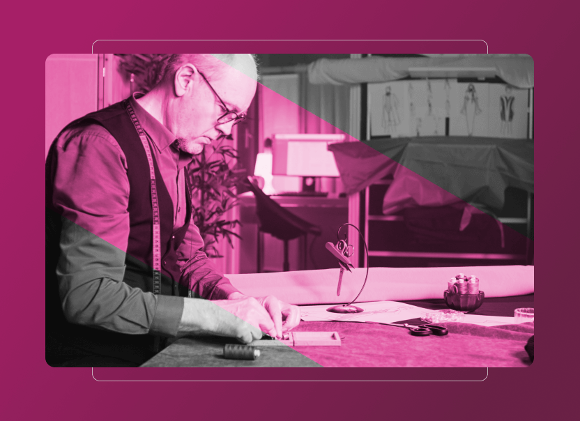 A tailor wearing glasses and a tape measure around his neck works at a table with fabric and sewing tools, in a studio with sketches on the wall. The image features a pink overlay, geometric shapes, and hints of Sustainability Cloud-inspired design.