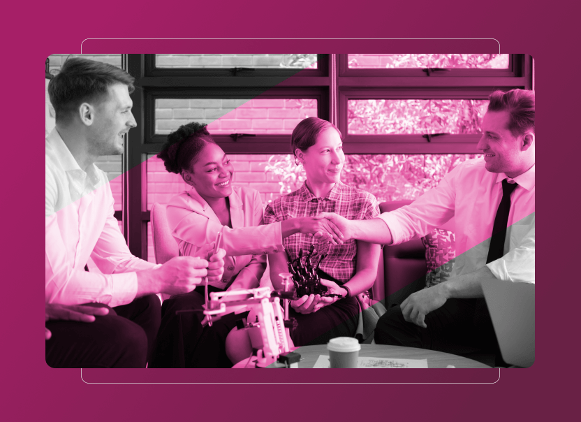 Four colleagues sit together, smiling and shaking hands in an office setting with a pink overlay; on the table are a robotic hand, coffee cup, and documents highlighting Sustainability Cloud initiatives.