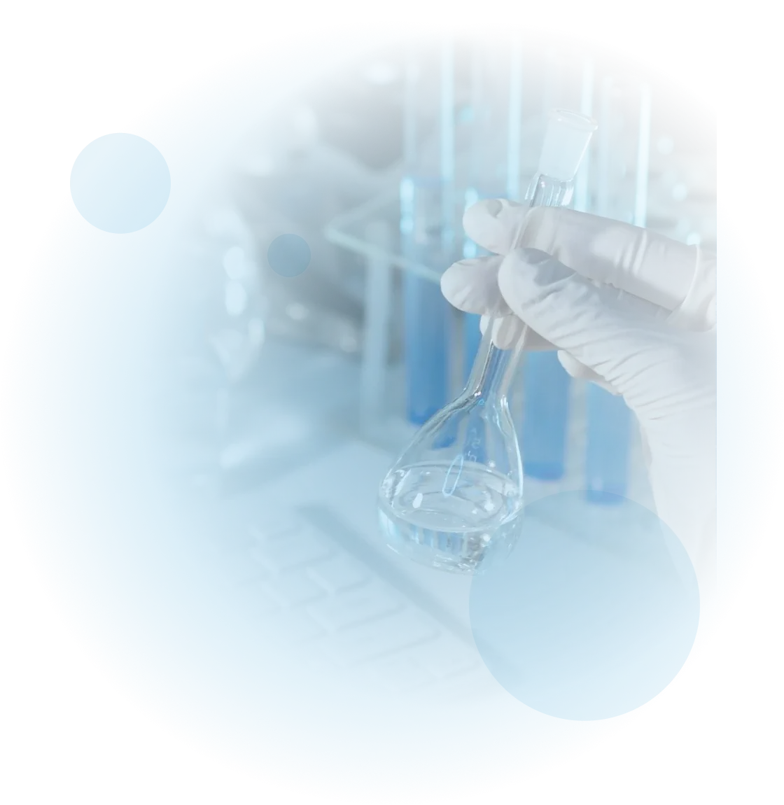 A gloved hand holds a laboratory flask containing a clear liquid, with test tubes and a keyboard visible in the blurred background.